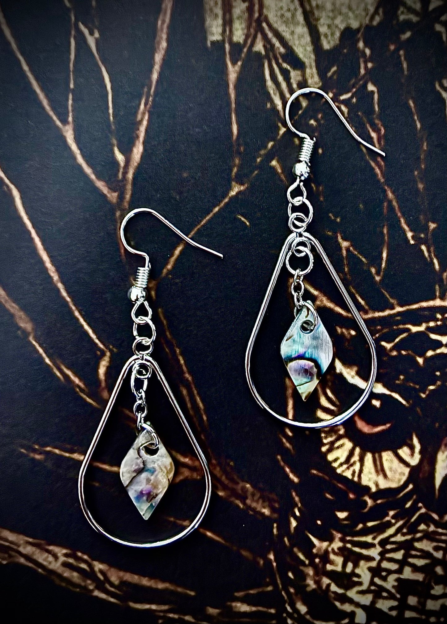 Teardrop-shaped earrings with metallic hooks on a dark owl background with abalone pearls from Martin Guitar Factory