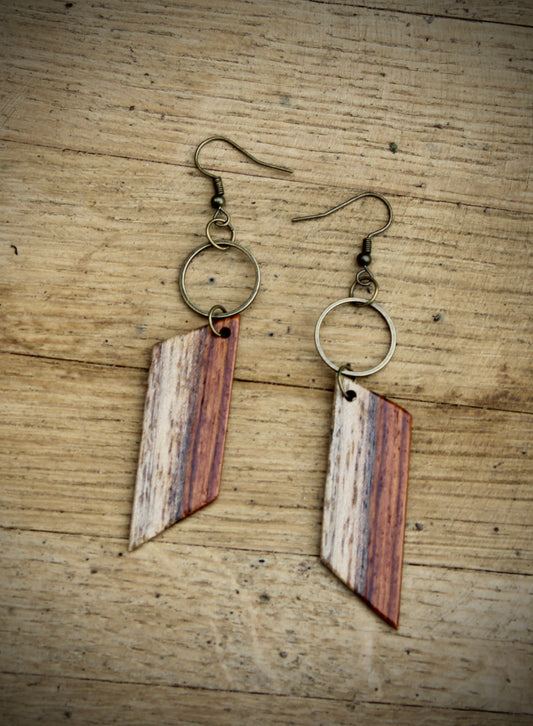 A pair of Rosewood Sap Hoop Earrings laid out on a wooden surface.