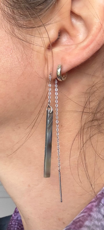 Close-up of a person wearing Abalone pearl threader earrings.