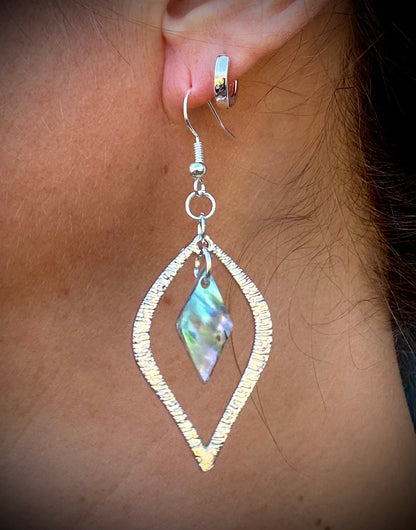 Silver earring with a diamond-shaped abalone pearl from Martin Guitar worn on an ear.