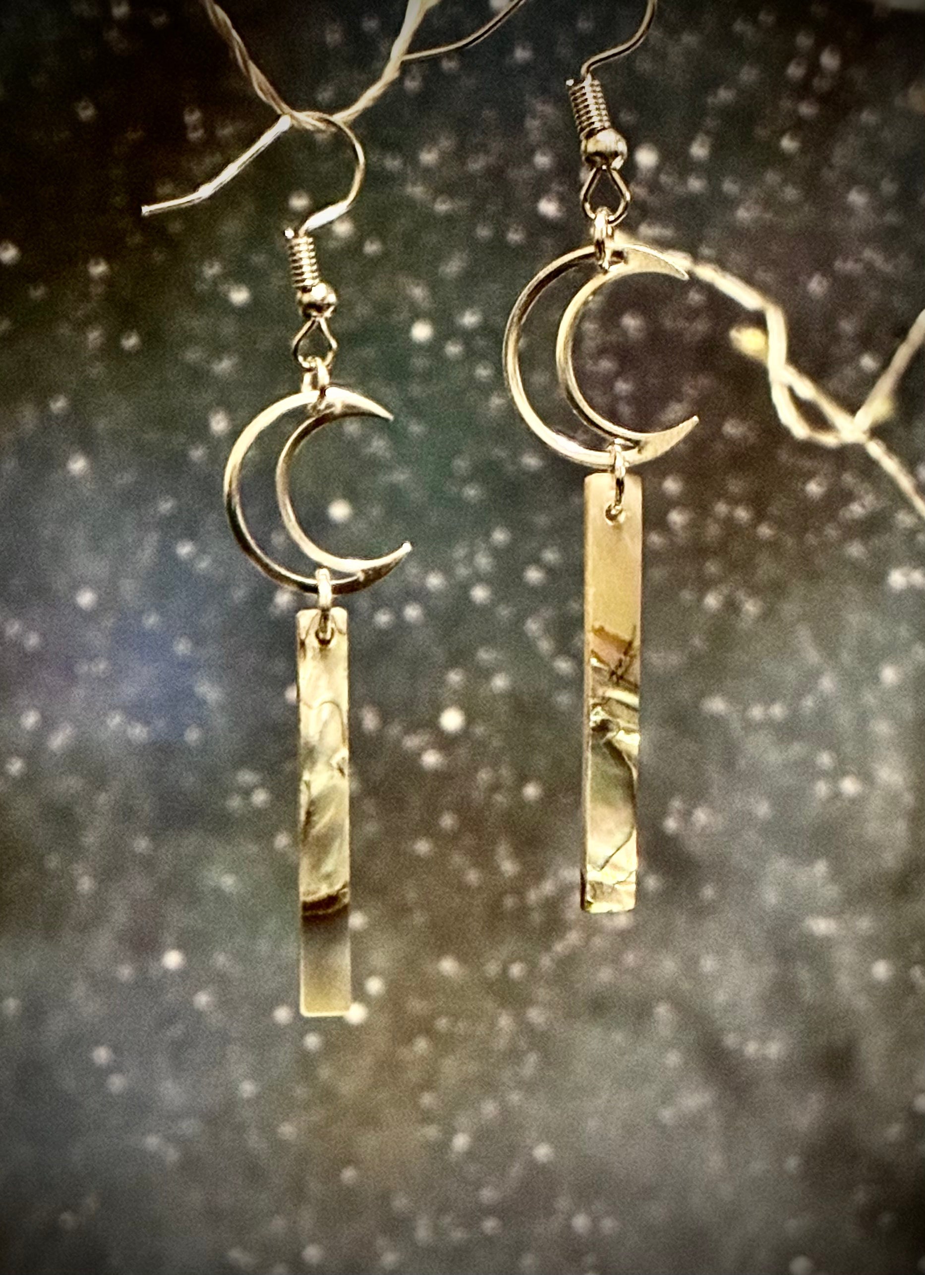 Silver hollow Cresent shaped jewelry with an abalone pearl bar drop from Martin guitar against celestial backdrop.