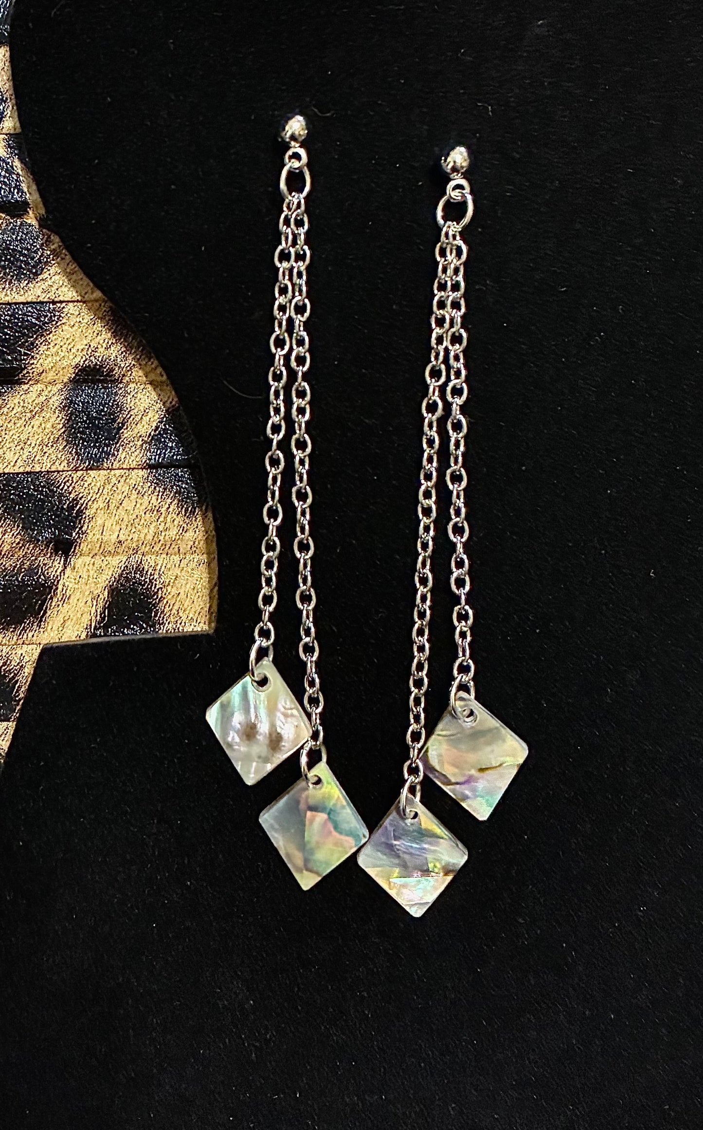Silver chain earrings with square pendant abalone pearls  on a black background sourced from Martin Guitar.