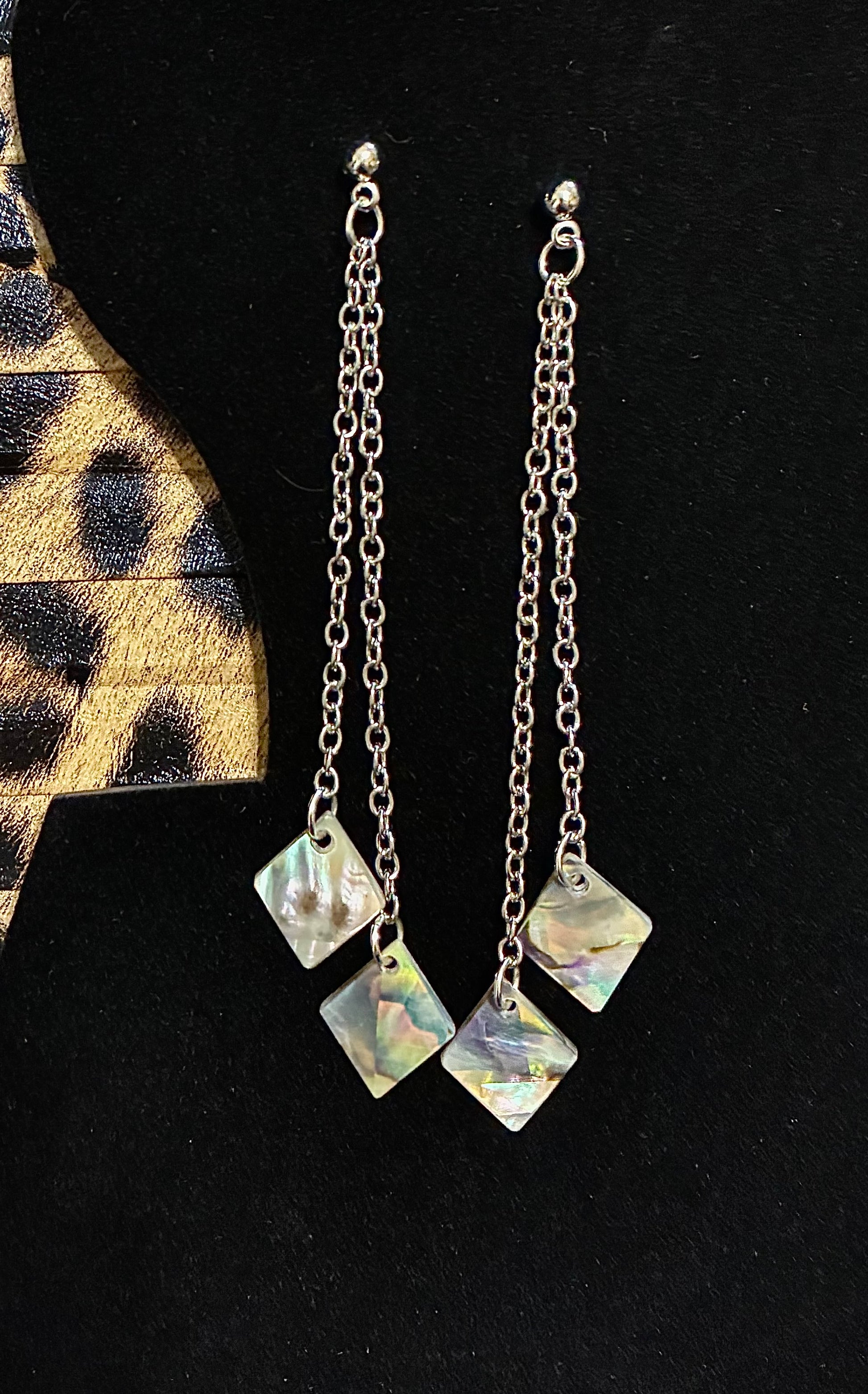 Silver chain earrings with square pendant abalone pearls  on a black background sourced from Martin Guitar.