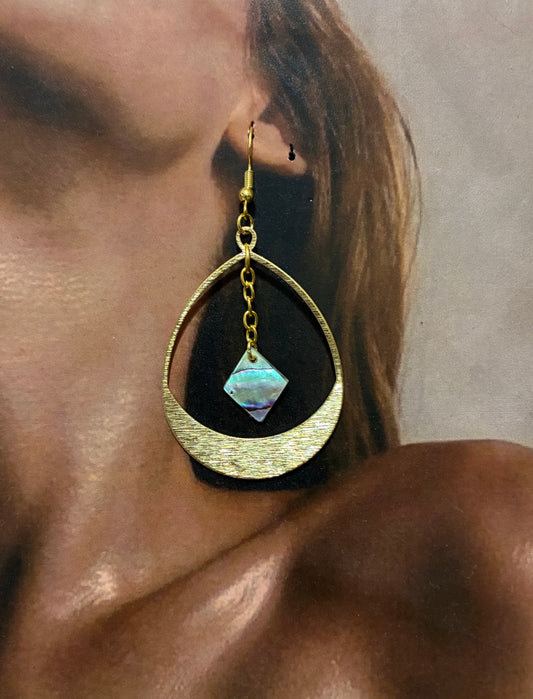 Gold hoop earring with an abalone pearl diamond worn by a woman