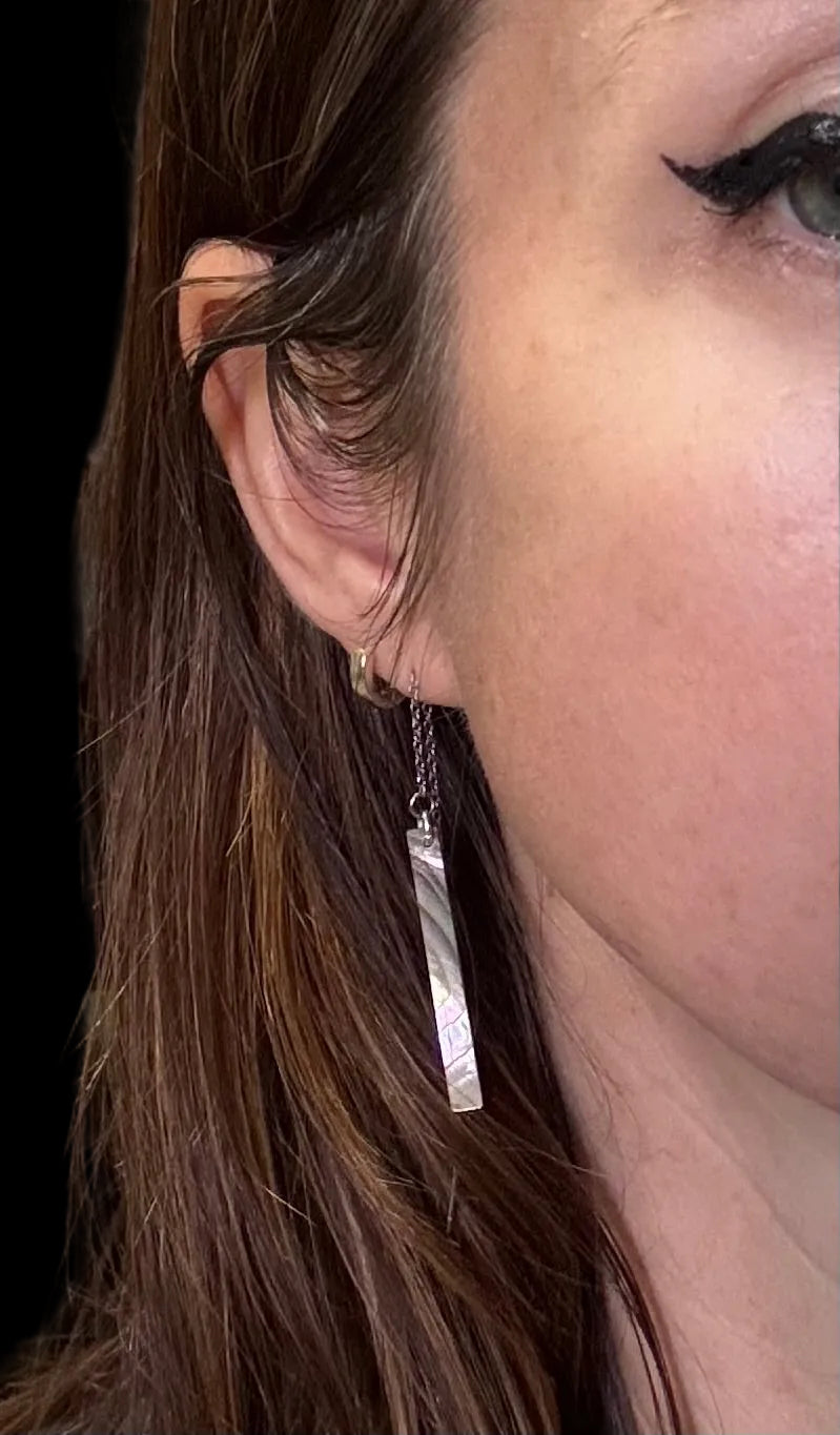 Close-up of a woman wearing a abalone pearl bar ear rope.