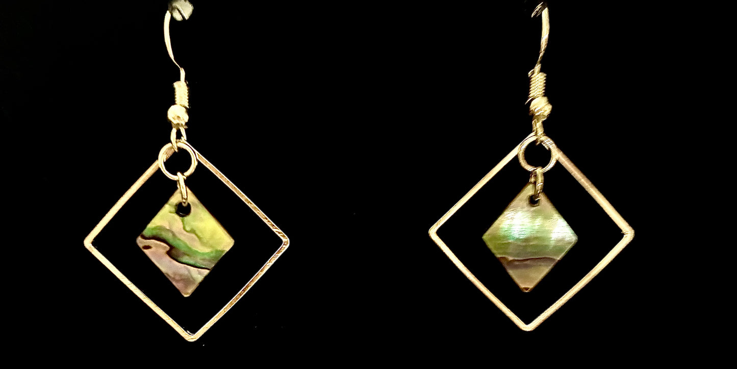 Pair of gold-framed earrings with green and gold Abalone Pearls from Martin Guitar on a black background