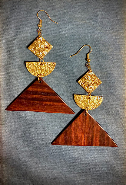 Pair of geometric earrings with hammered gold and exotic guitar wood design on a gray background