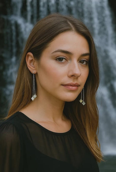 Woman standing in front of waterfall wearing double silver chain earrings with abalone pearl sourced from Martin guitar factory.